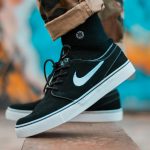 Close-up of black sneakers with camouflage pants, showcasing urban style.